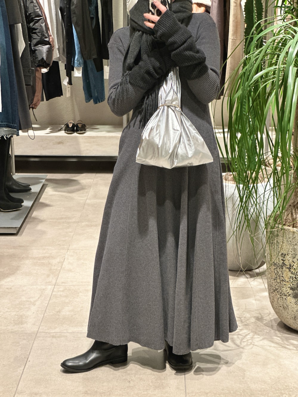 グレー系のワンピース、シルバー系のトートバッグ、ブラック系のブーツを着用したレディースの冬コーディネートの3枚目の写真