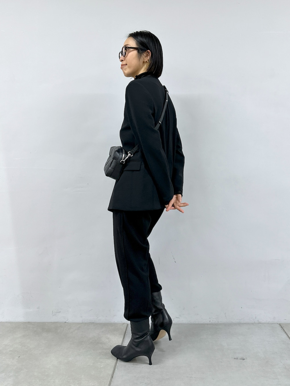 ブラック系のTシャツ/カットソー、ブラック系のパンツ、ブラック系のショルダーバッグを着用したレディースの冬コーディネートの3枚目の写真