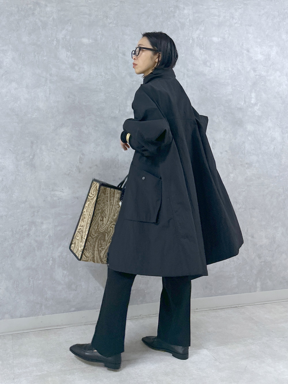 ブラック系のマウンテンパーカー、ブラック系のスラックス、ブラック系のトートバッグを着用したレディースの春コーディネートの3枚目の写真