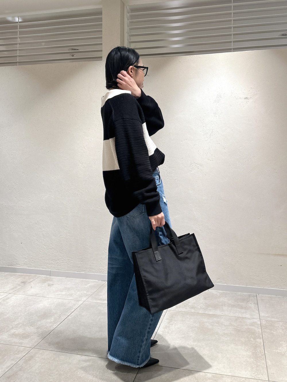 ブルー系のデニムパンツ、ブラック系のニット/セーター、ブラック系のブーツを着用したレディースの冬コーディネートの2枚目の写真