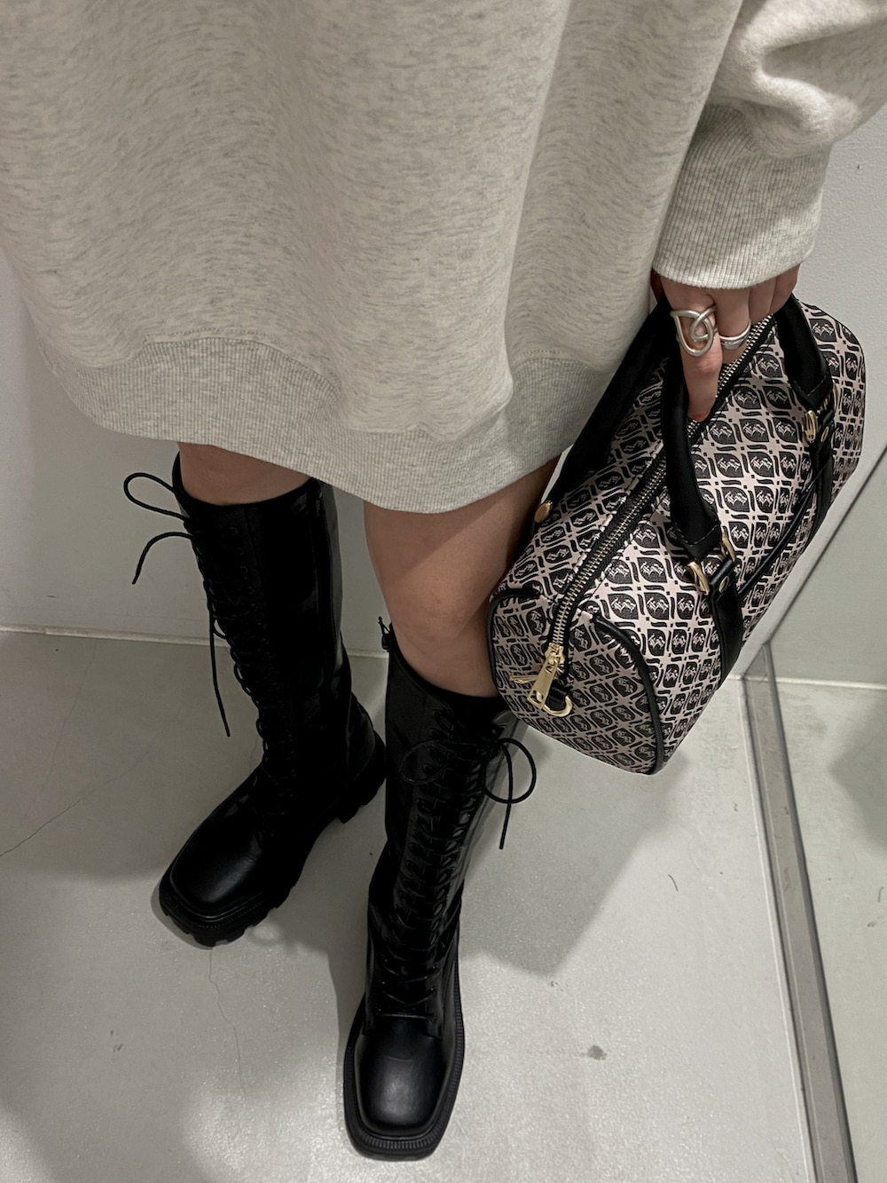 ブラック系のボストンバッグ、ホワイト系のスウェット、ブラック系のブーツを着用したレディースの夏コーディネートの3枚目の写真