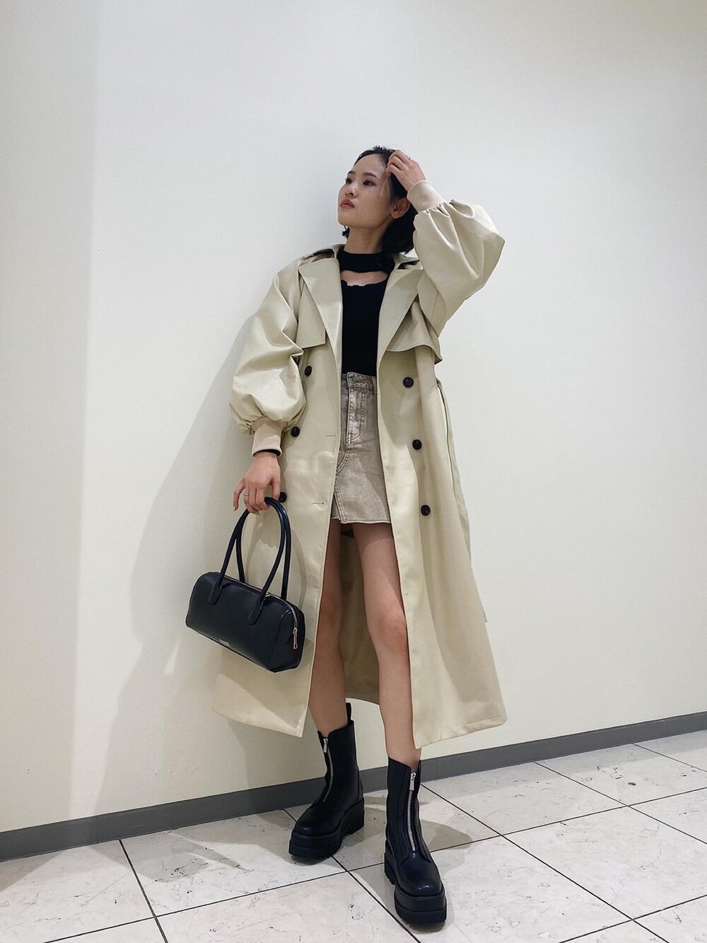 ブラック系のボストンバッグ、ブラック系のブーツ、ホワイト系のトレンチコートを着用したレディースの冬コーディネートの2枚目の写真