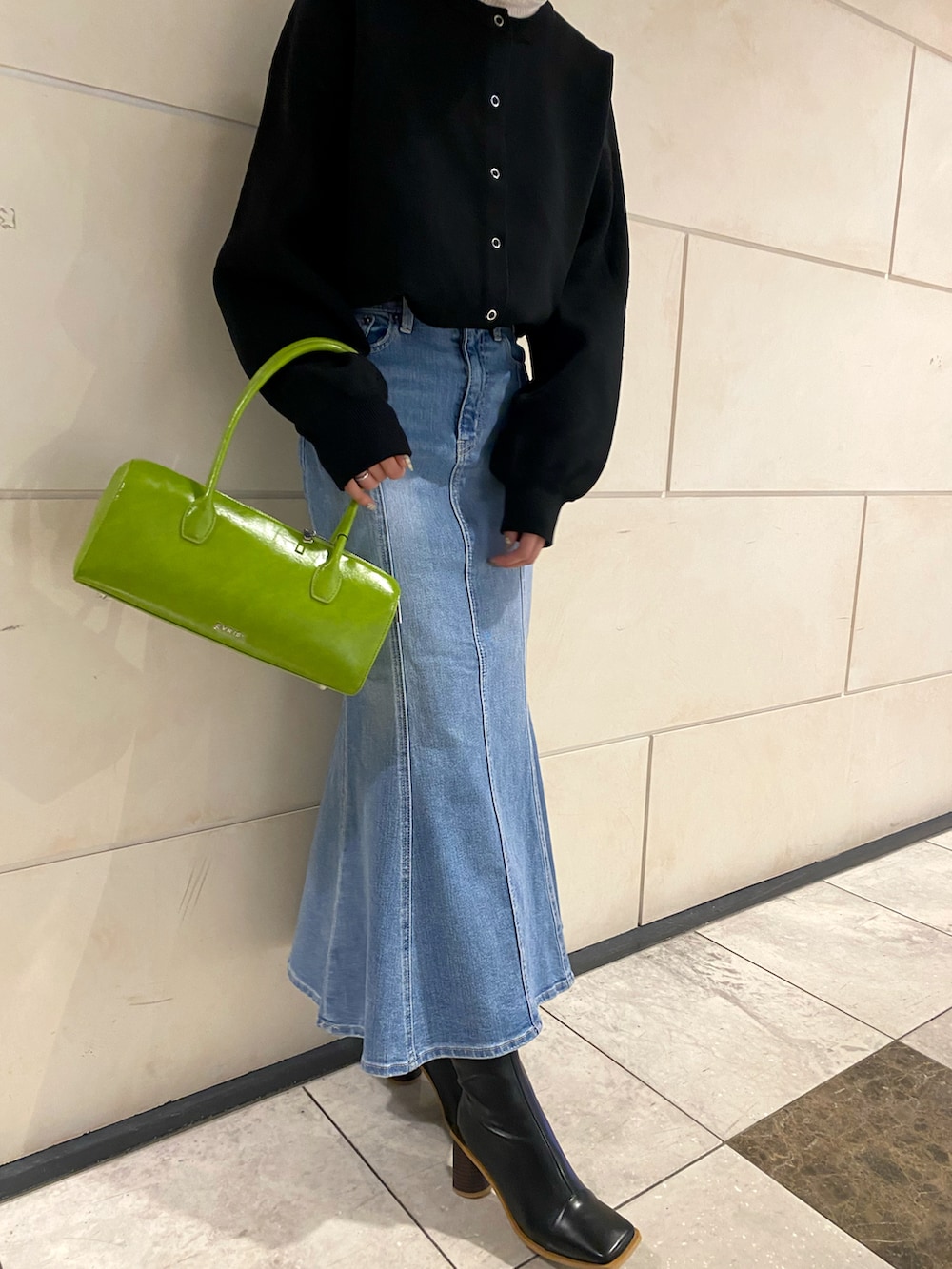 ブラック系のカーディガン/ボレロ、ブルー系のデニムスカート、グリーン系のボストンバッグを着用したレディースの冬コーディネートの3枚目の写真