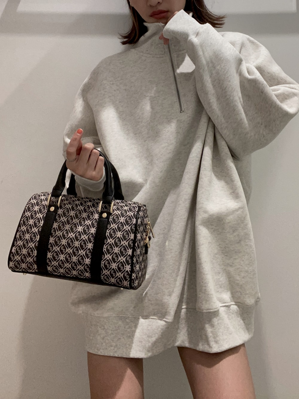 ブラック系のボストンバッグ、ホワイト系のスウェット、ブラック系のブーツを着用したレディースの夏コーディネートの2枚目の写真