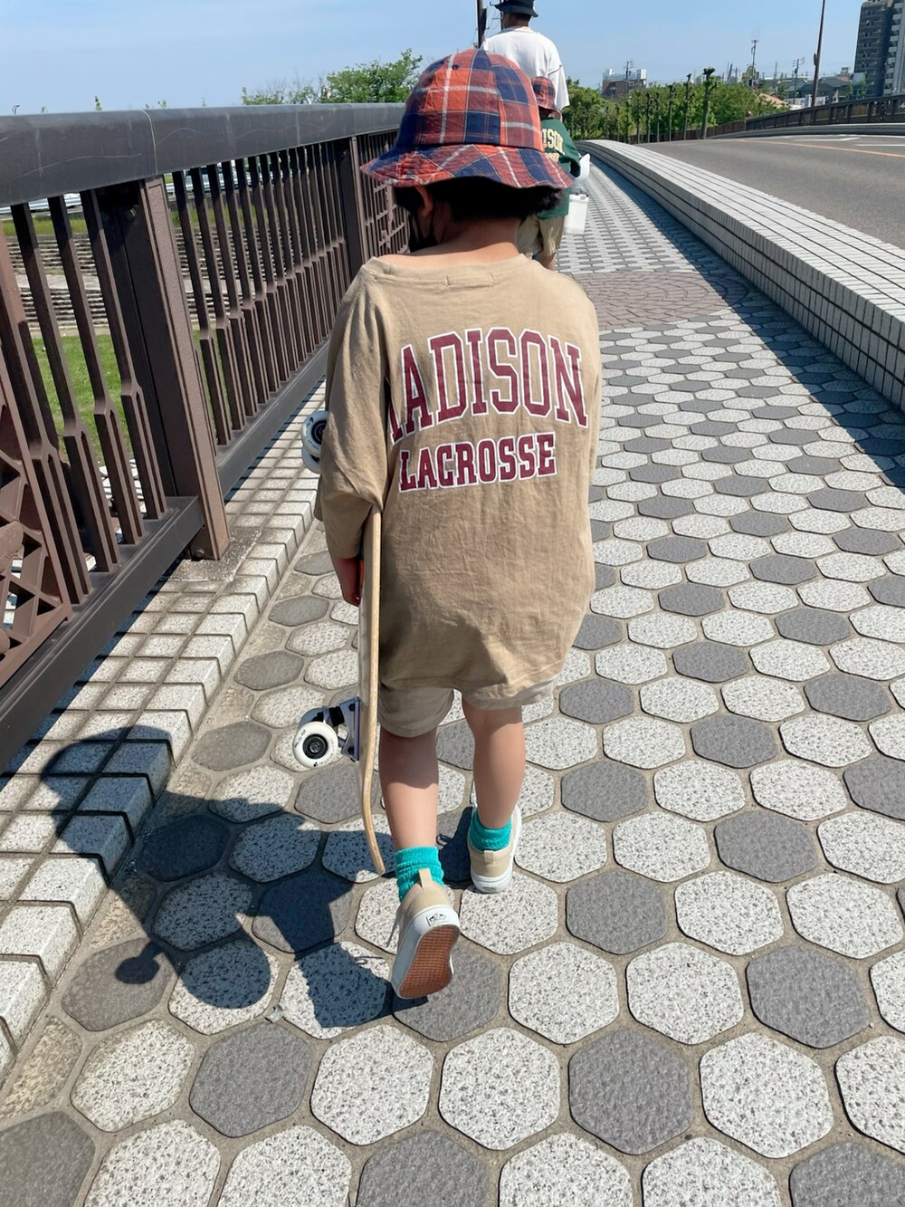 ベージュ系のTシャツ/カットソー、ベージュ系のスニーカー、オレンジ系のハットを着用したキッズの春コーディネートの3枚目の写真