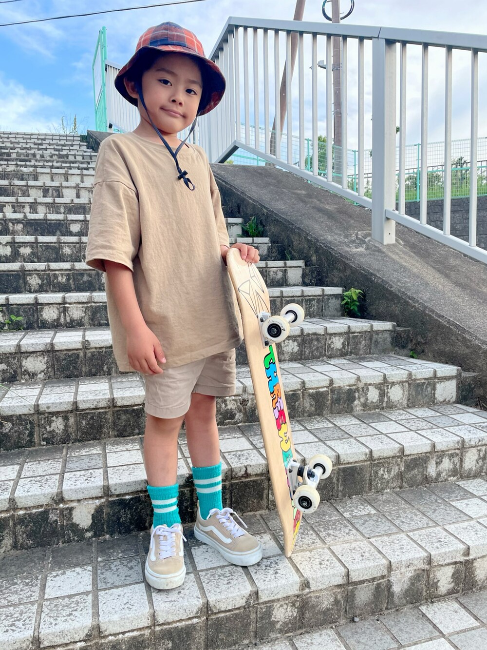 ベージュ系のTシャツ/カットソー、ベージュ系のスニーカー、オレンジ系のハットを着用したキッズの春コーディネートの2枚目の写真