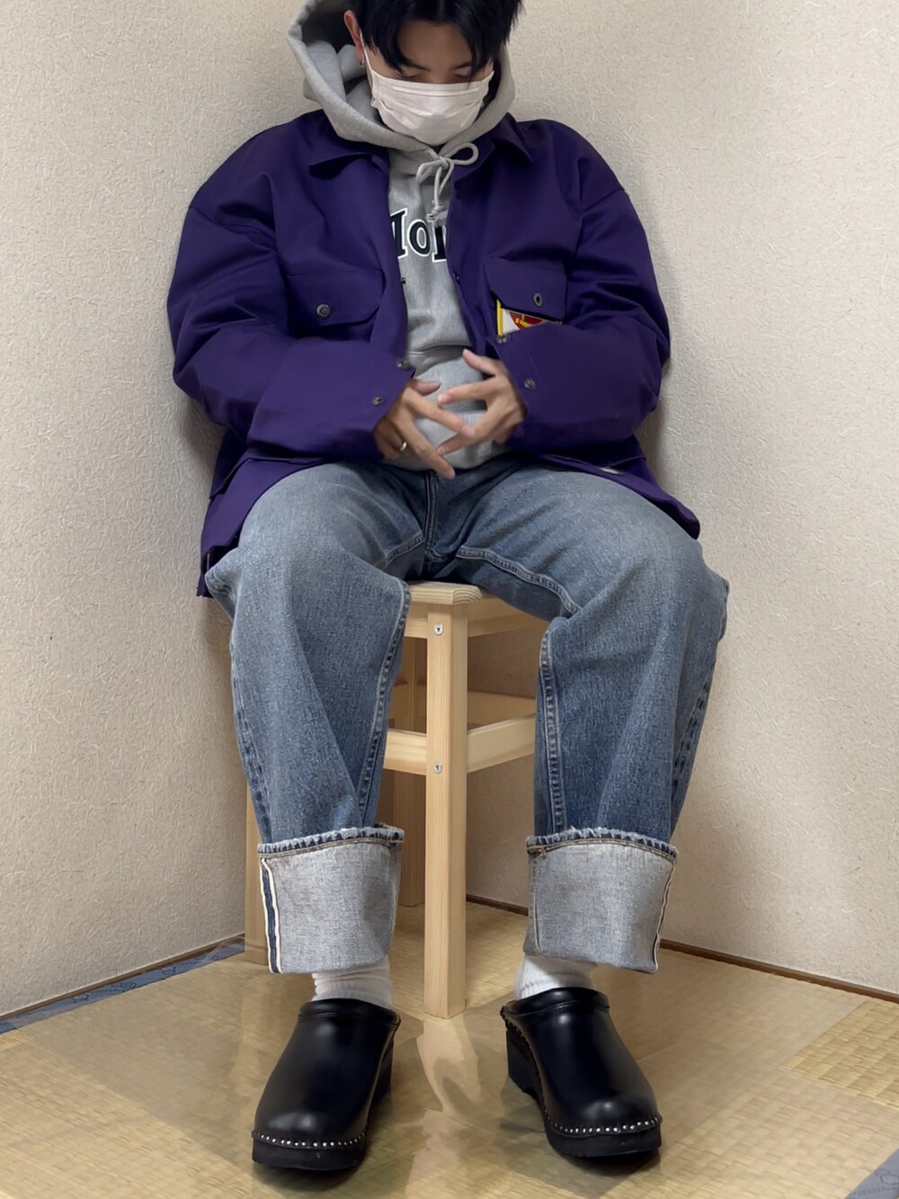 パープル系のカバーオール、ブルー系のデニムパンツ、ブラック系のシューズを着用したメンズの秋コーディネートの2枚目の写真