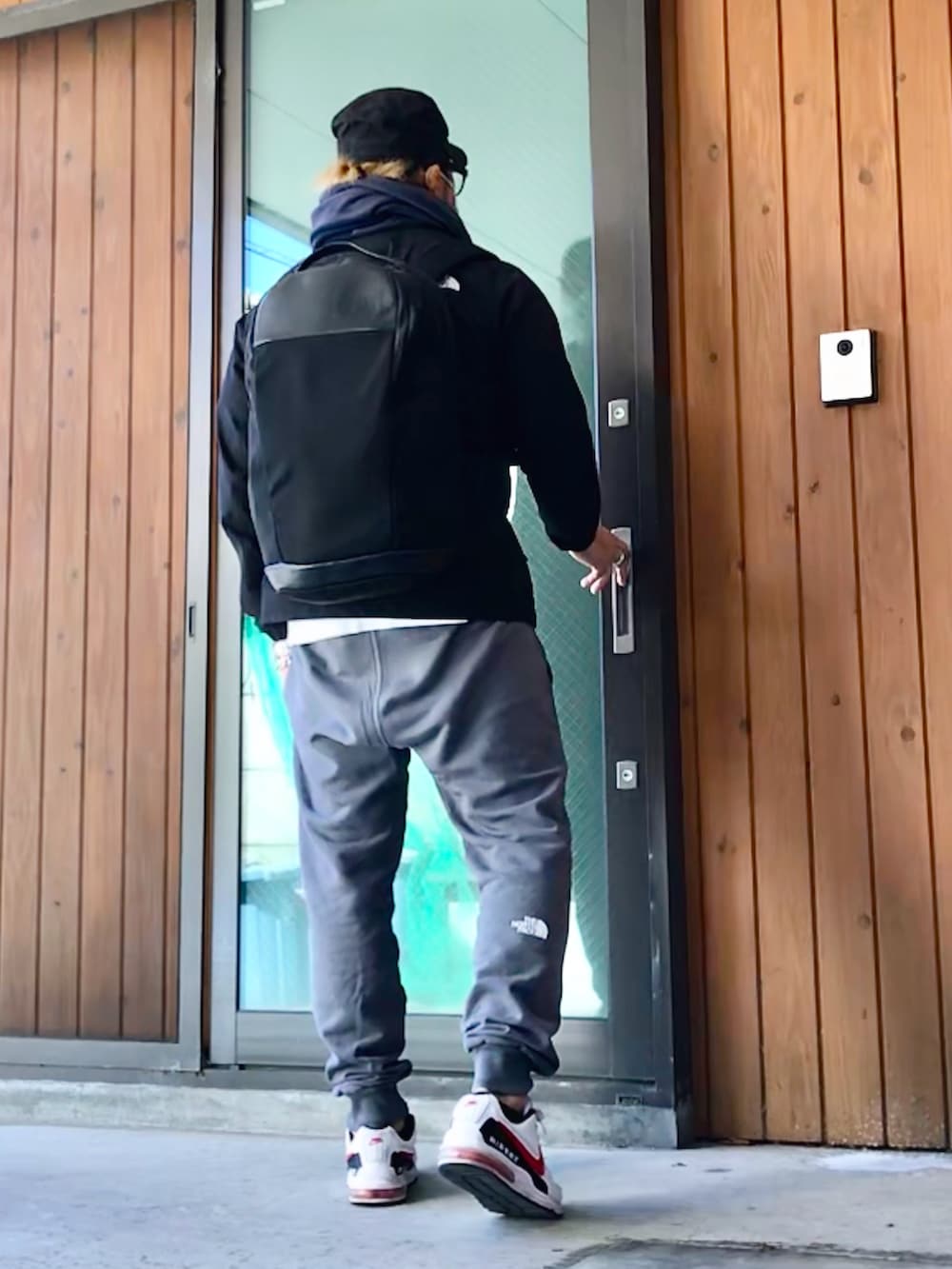 ブラック系のナイロンジャケット、ブラック系のバックパック/リュック、グレー系のスウェットパンツを着用したメンズの冬コーディネートの2枚目の写真