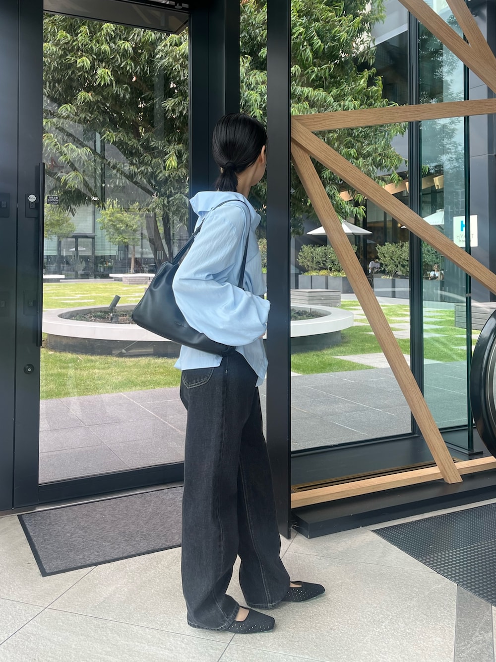 ブルー系のシャツ/ブラウス、ブラック系のショルダーバッグ、ブラック系のデニムパンツを着用したレディースの秋コーディネートの2枚目の写真
