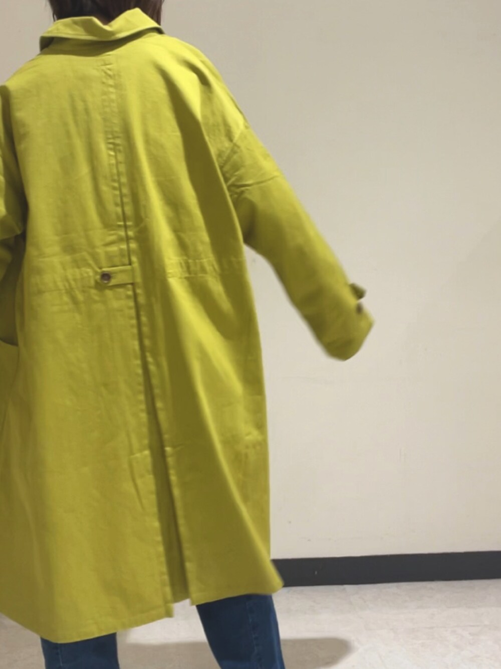 グリーン系のステンカラーコート、ブルー系のデニムパンツ、ホワイト系のTシャツ/カットソーを着用したレディースの冬コーディネートの3枚目の写真