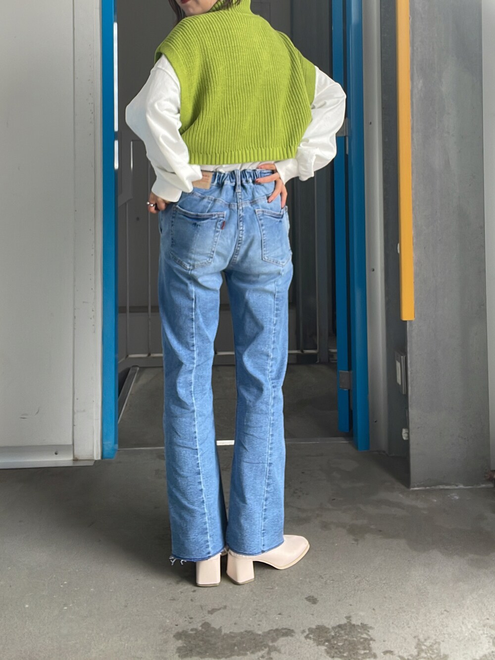 グリーン系のベスト、ブルー系のデニムパンツを着用したレディースの冬コーディネートの2枚目の写真