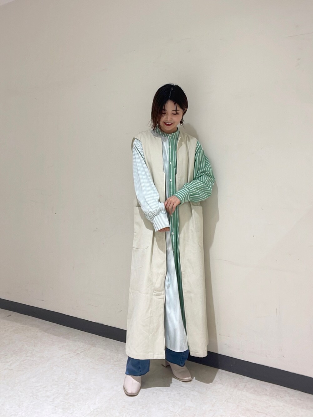 ホワイト系のカーディガン/ボレロ、グリーン系のシャツワンピース、ブルー系のデニムパンツを着用したレディースの冬コーディネートの4枚目の写真