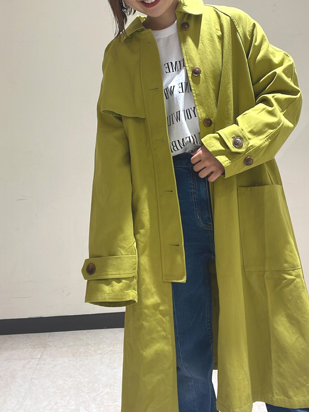 グリーン系のステンカラーコート、ブルー系のデニムパンツ、ホワイト系のTシャツ/カットソーを着用したレディースの冬コーディネートの2枚目の写真