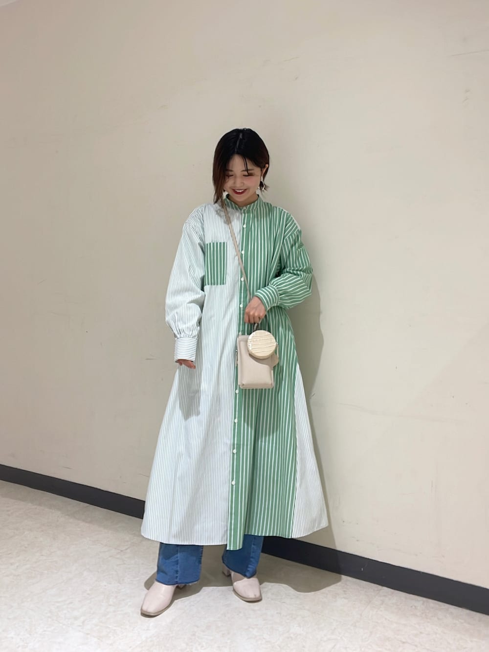 ホワイト系のカーディガン/ボレロ、グリーン系のシャツワンピース、ブルー系のデニムパンツを着用したレディースの冬コーディネートの3枚目の写真