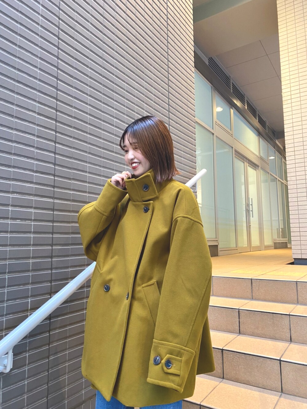 グリーン系のピーコートを着用したレディースの冬コーディネートの2枚目の写真