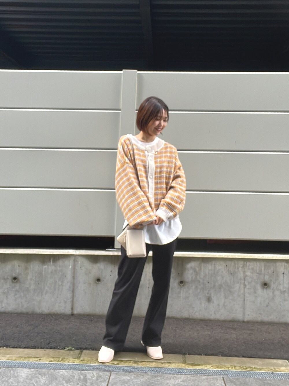 オレンジ系のニット/セーター、ブラック系のその他パンツを着用したレディースの冬コーディネートの2枚目の写真