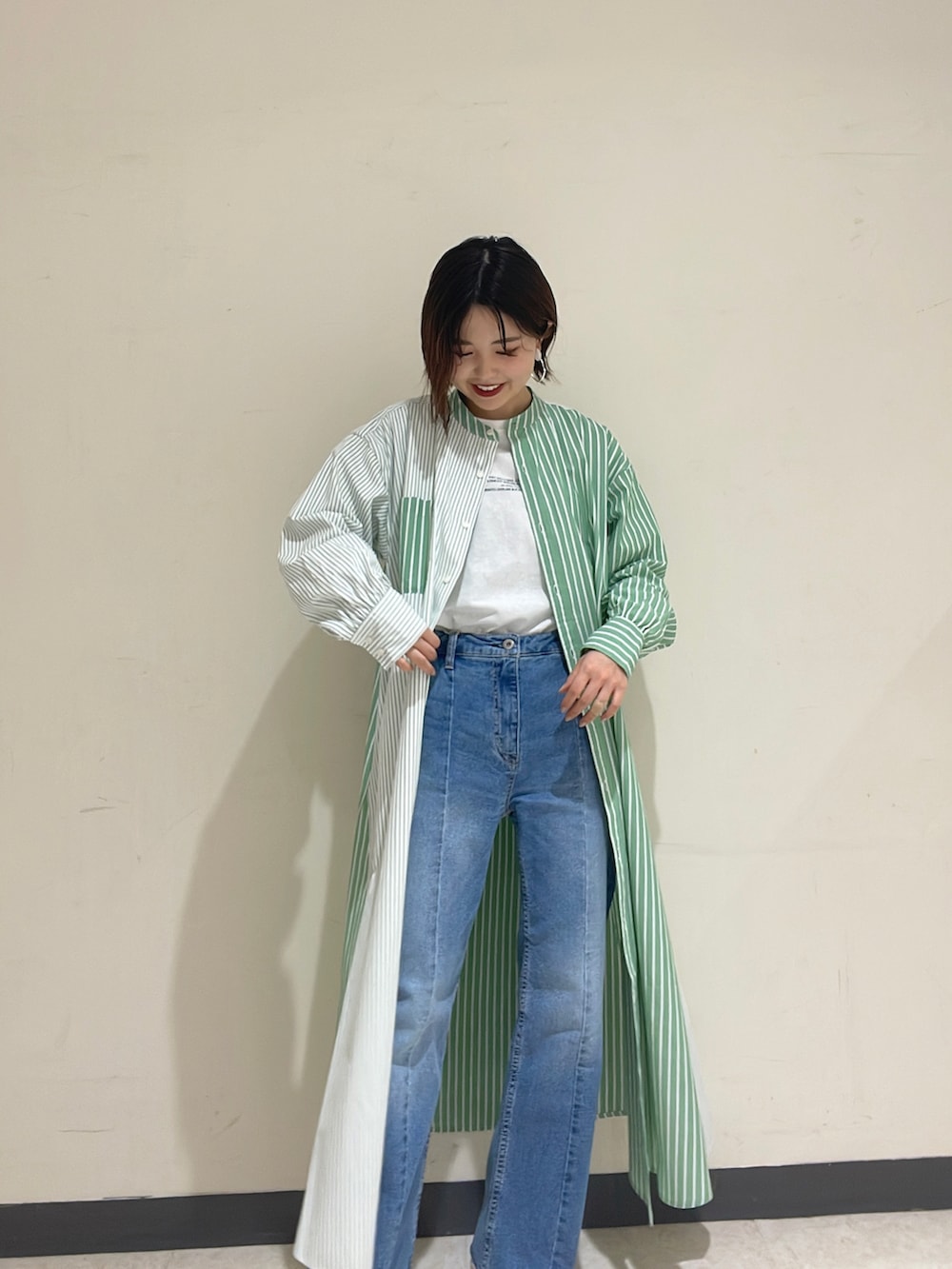 グリーン系のシャツワンピース、ブルー系のベスト、ブルー系のデニムパンツを着用したレディースの冬コーディネートの3枚目の写真