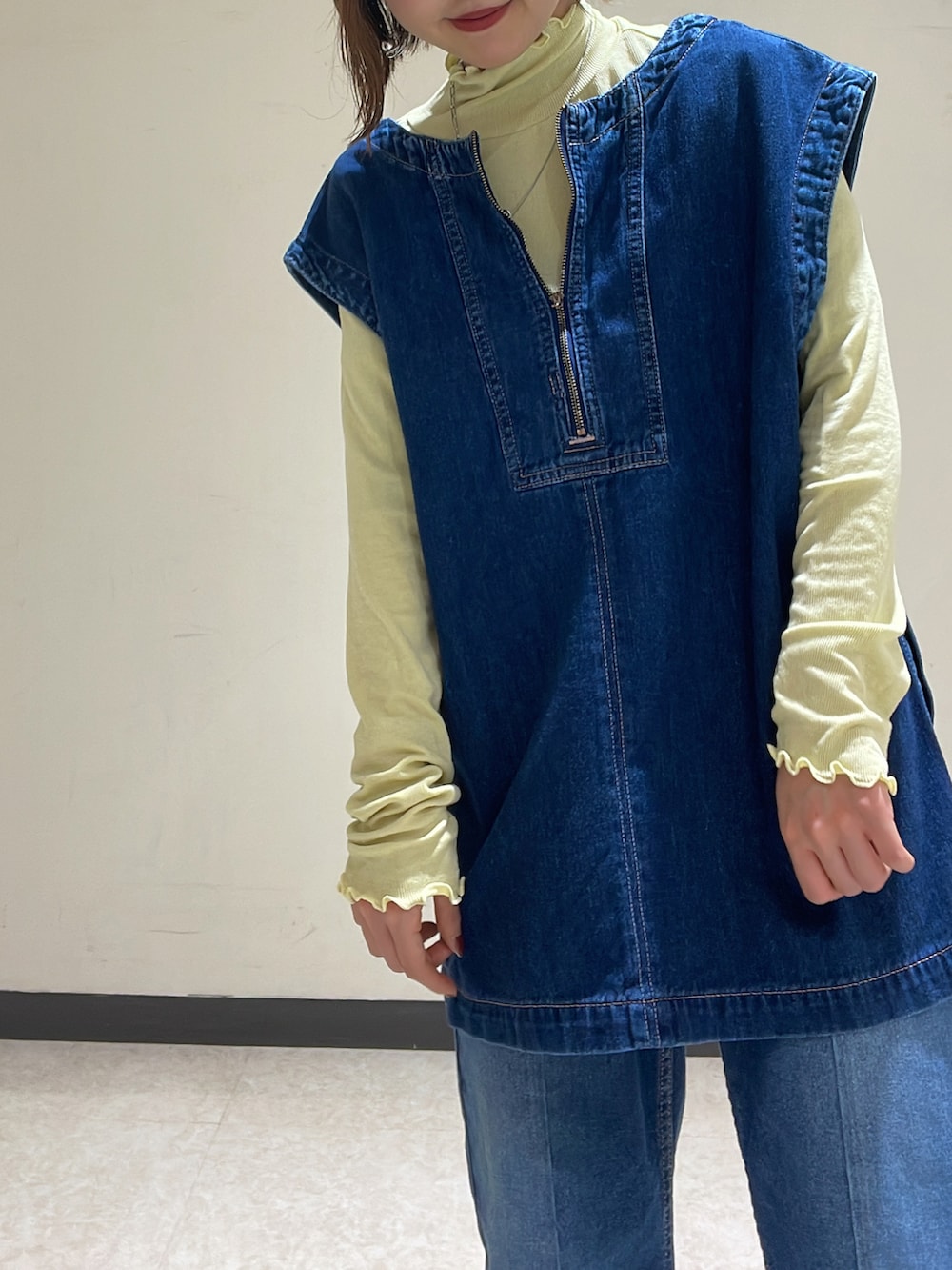 ブルー系のベスト、イエロー系のTシャツ/カットソー、ブルー系のデニムパンツを着用したレディースの冬コーディネートの2枚目の写真