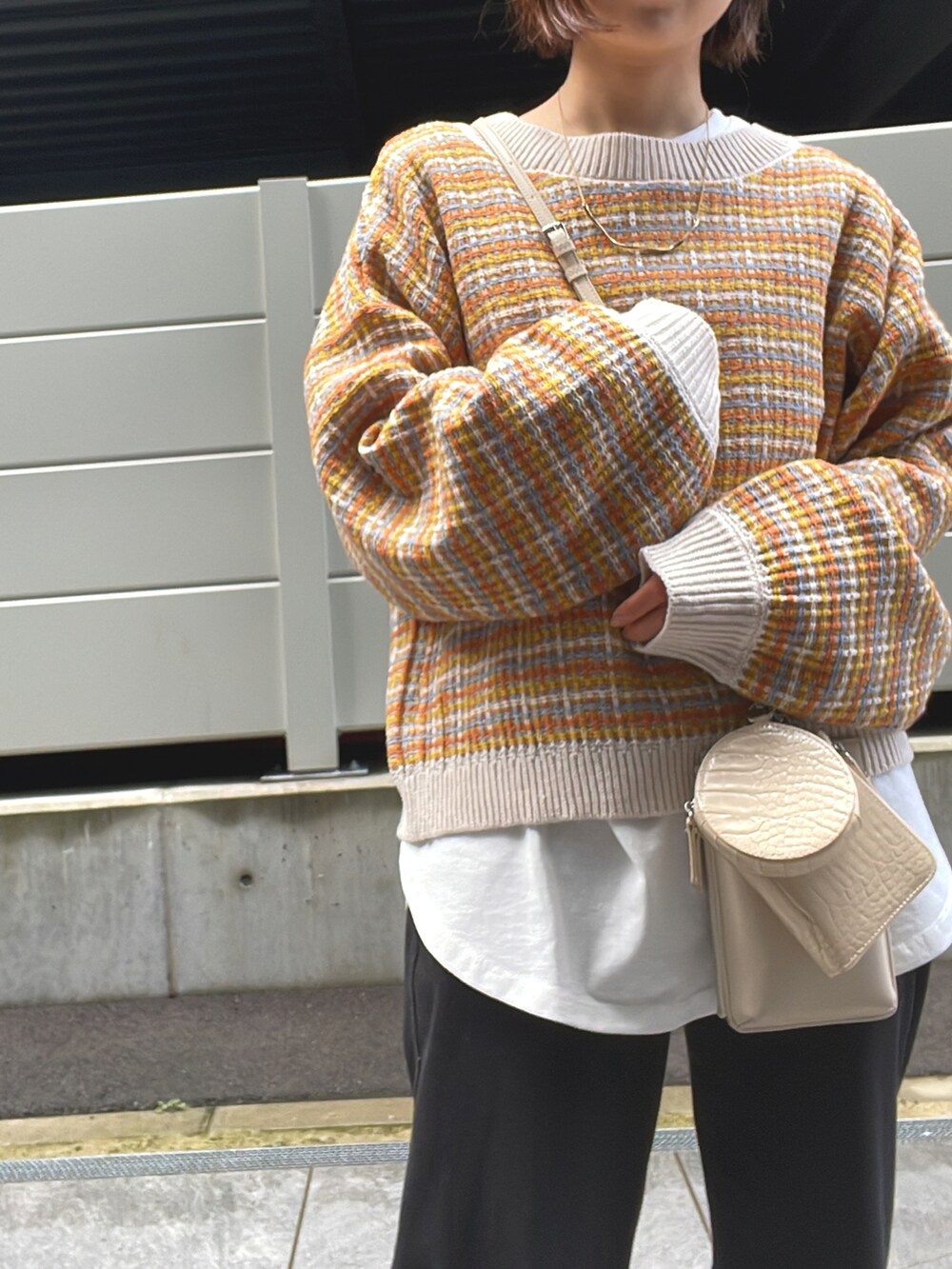 オレンジ系のニット/セーター、ブラック系のその他パンツを着用したレディースの冬コーディネートの3枚目の写真