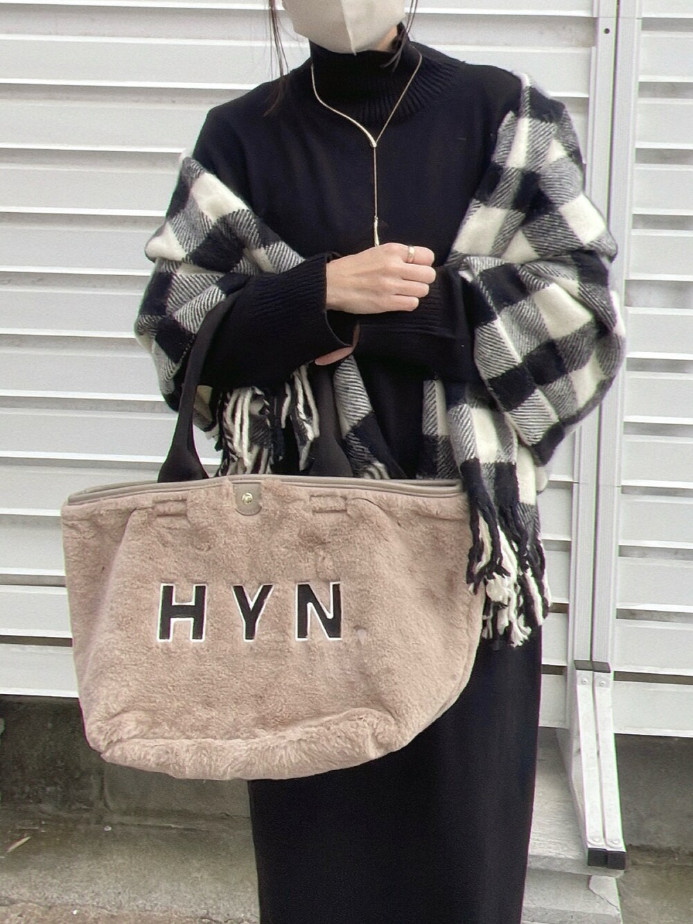 ブラック系のワンピース、ホワイト系のトートバッグ、ブラック系のブーツを着用したレディースの秋コーディネートの3枚目の写真