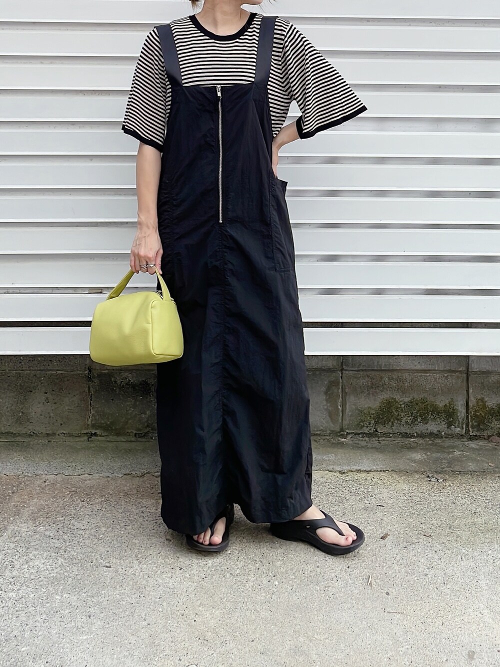 ブラック系のニット/セーター、ブラック系のワンピース、イエロー系のショルダーバッグを着用したレディースの夏コーディネートの2枚目の写真