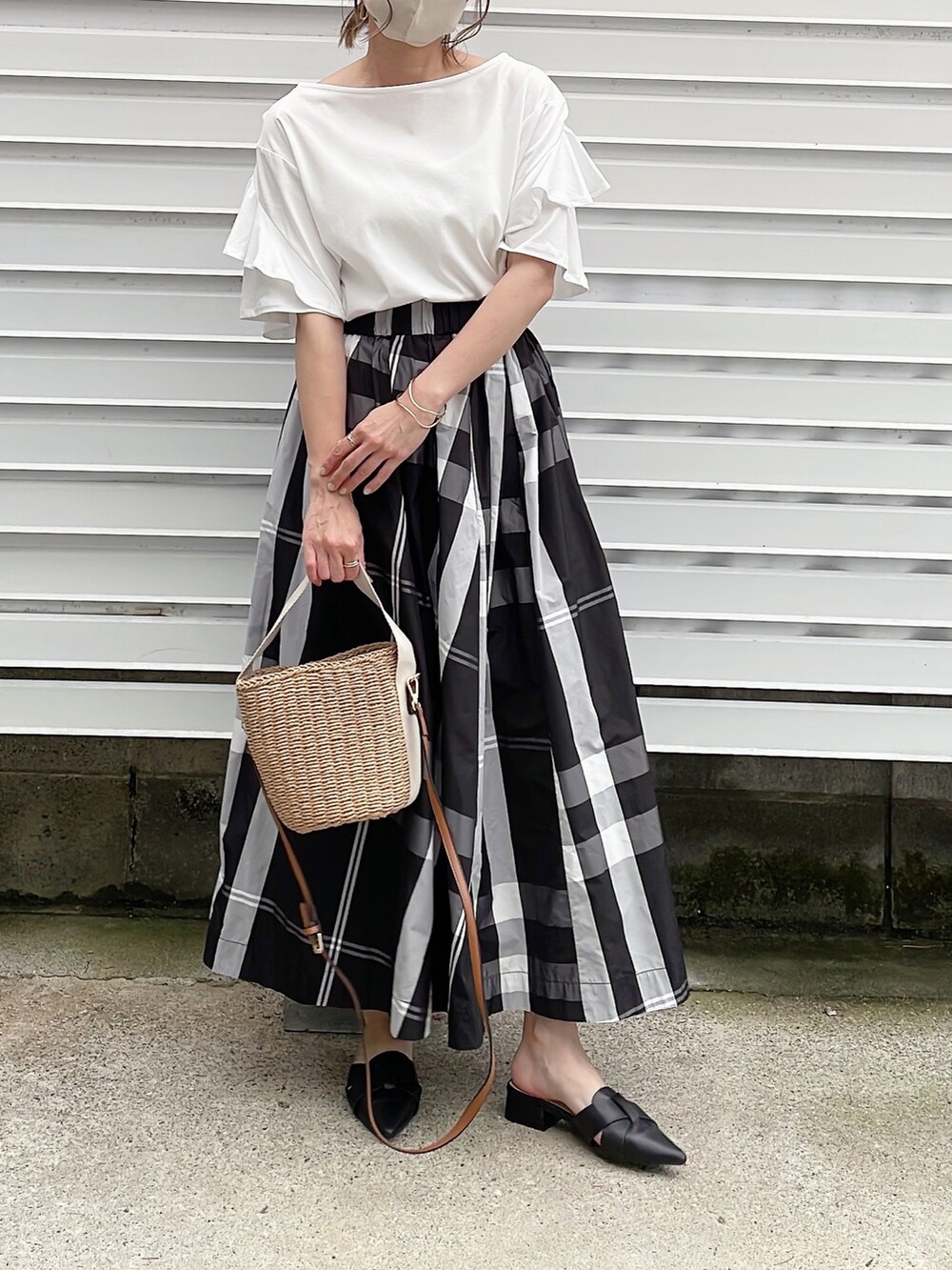 ホワイト系のTシャツ/カットソー、ブラック系のスカート、ベージュ系のかごバッグを着用したレディースの夏コーディネートの2枚目の写真