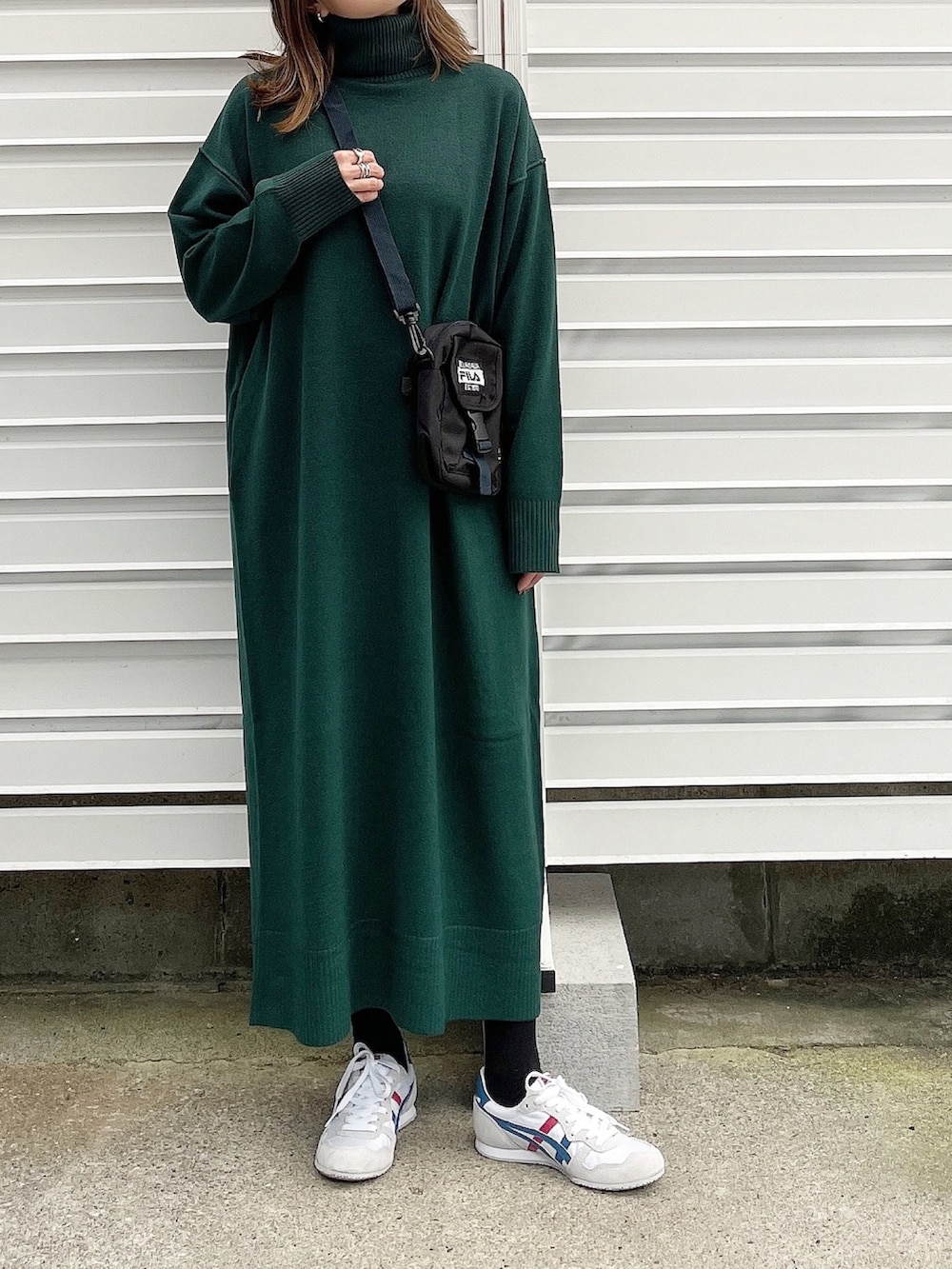 グリーン系のワンピース、ブラック系のショルダーバッグ、ホワイト系のスニーカーを着用したレディースの冬コーディネートの2枚目の写真