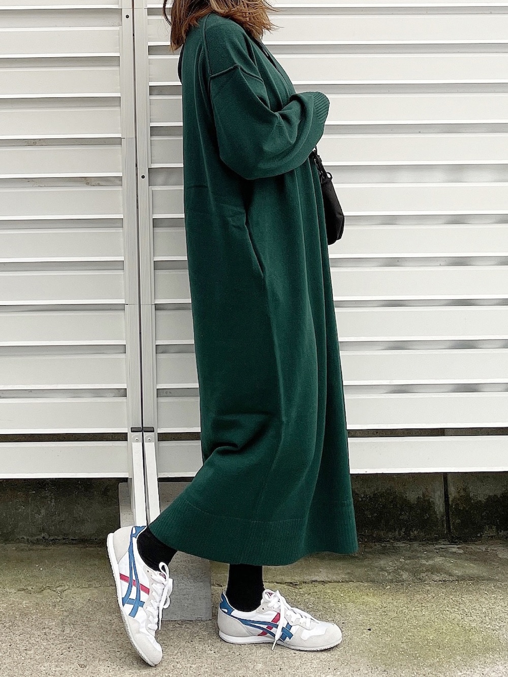 グリーン系のワンピース、ブラック系のショルダーバッグ、ホワイト系のスニーカーを着用したレディースの冬コーディネートの3枚目の写真