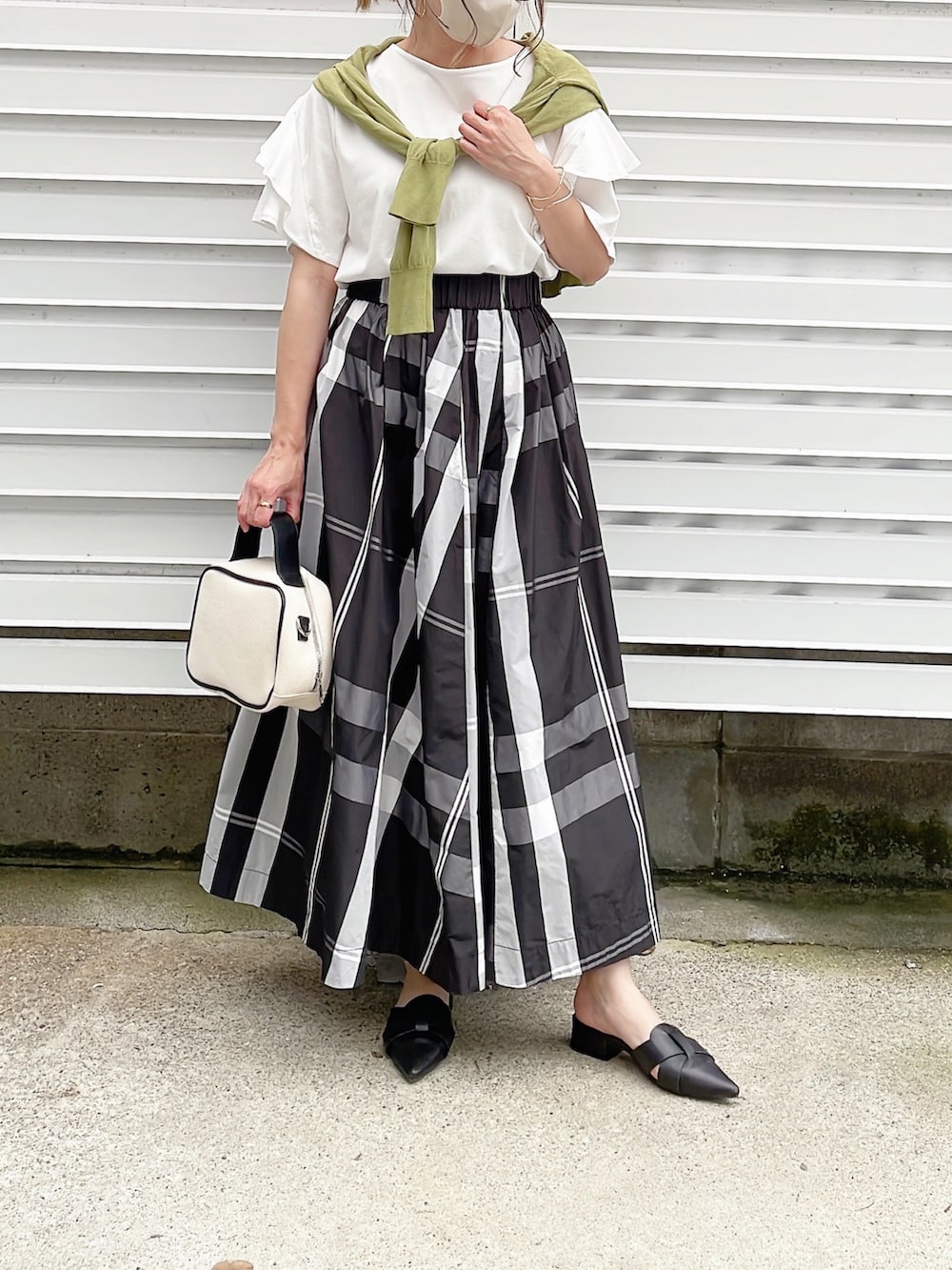 ホワイト系のTシャツ/カットソー、ブラック系のスカート、ベージュ系のかごバッグを着用したレディースの夏コーディネートの3枚目の写真