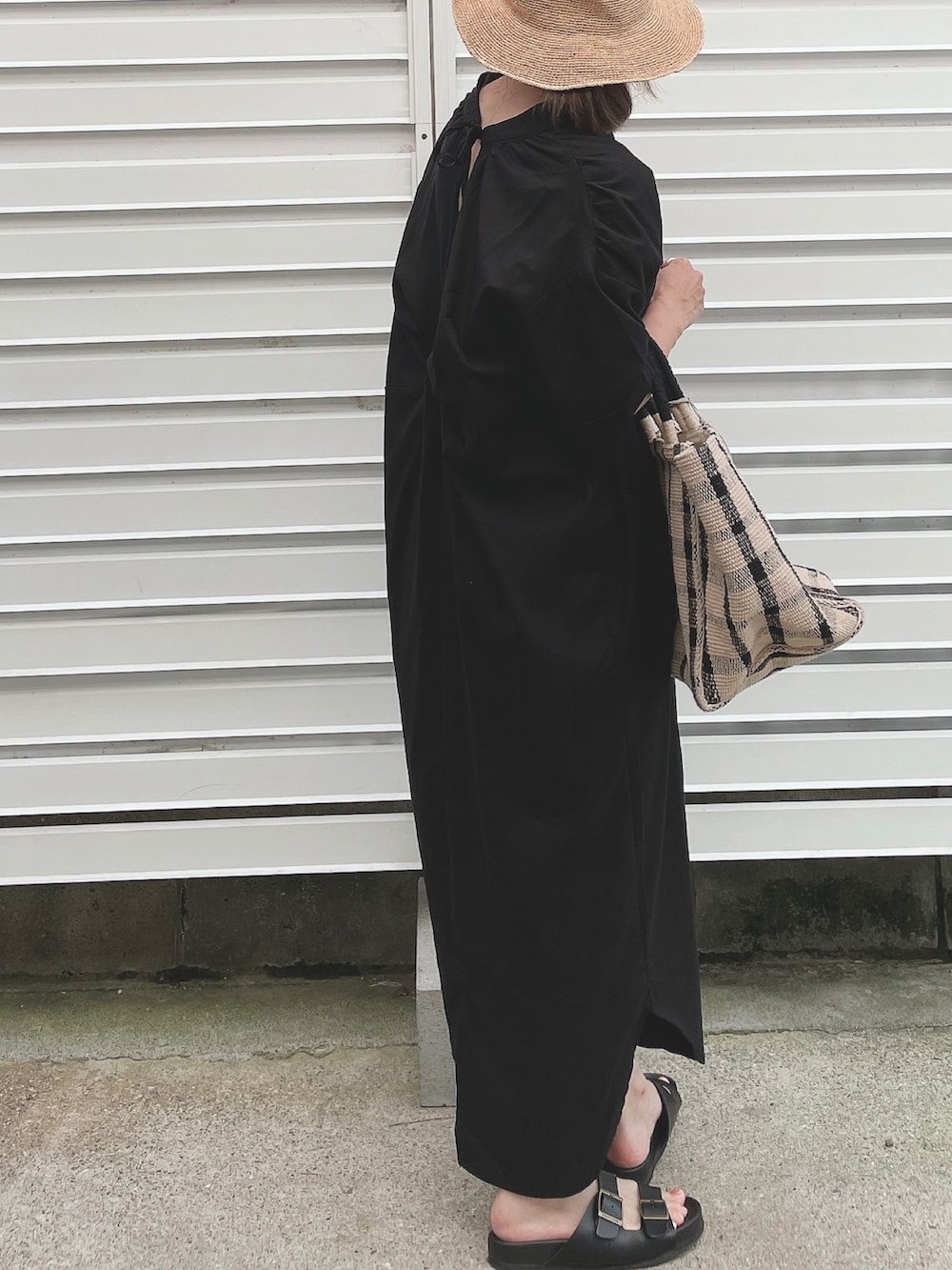 ブラック系のワンピース、ブラック系のサンダル、ブラック系のトートバッグを着用したレディースの夏コーディネートの2枚目の写真