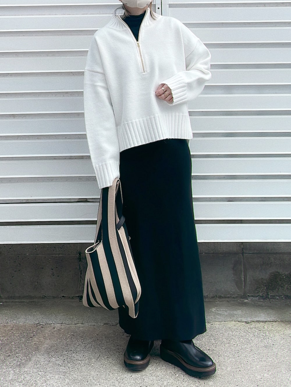 ホワイト系のニット/セーター、ブラック系のブーツ、ベージュ系のトートバッグを着用したレディースの秋コーディネートの2枚目の写真