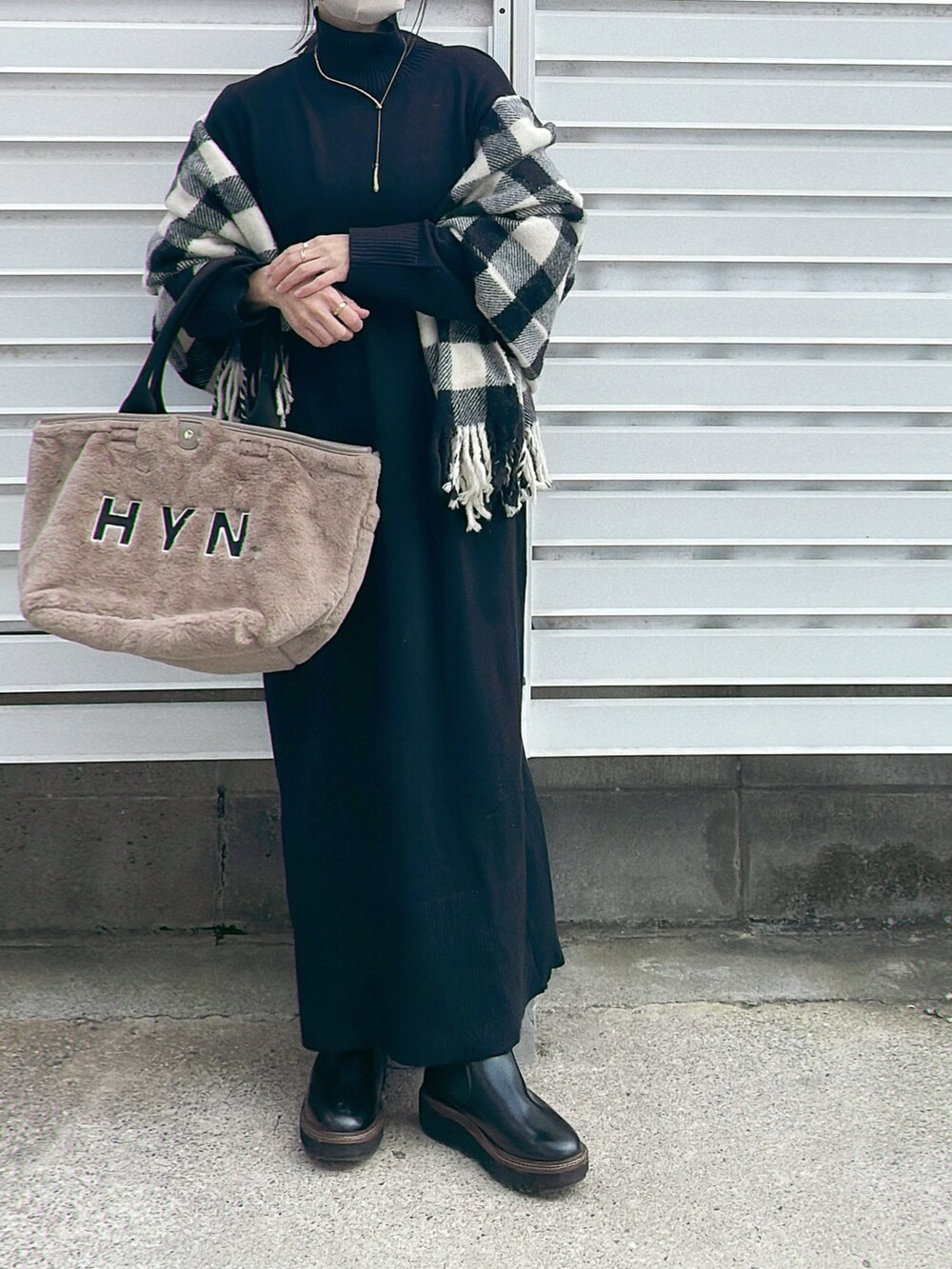 ブラック系のワンピース、ホワイト系のトートバッグ、ブラック系のブーツを着用したレディースの秋コーディネートの2枚目の写真