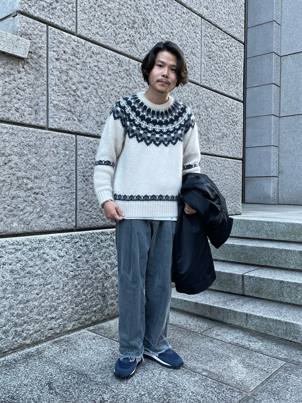 ブラック系のステンカラーコート、ブラック系のデニムパンツ、ブルー系のスニーカーを着用したメンズの冬コーディネートの2枚目の写真