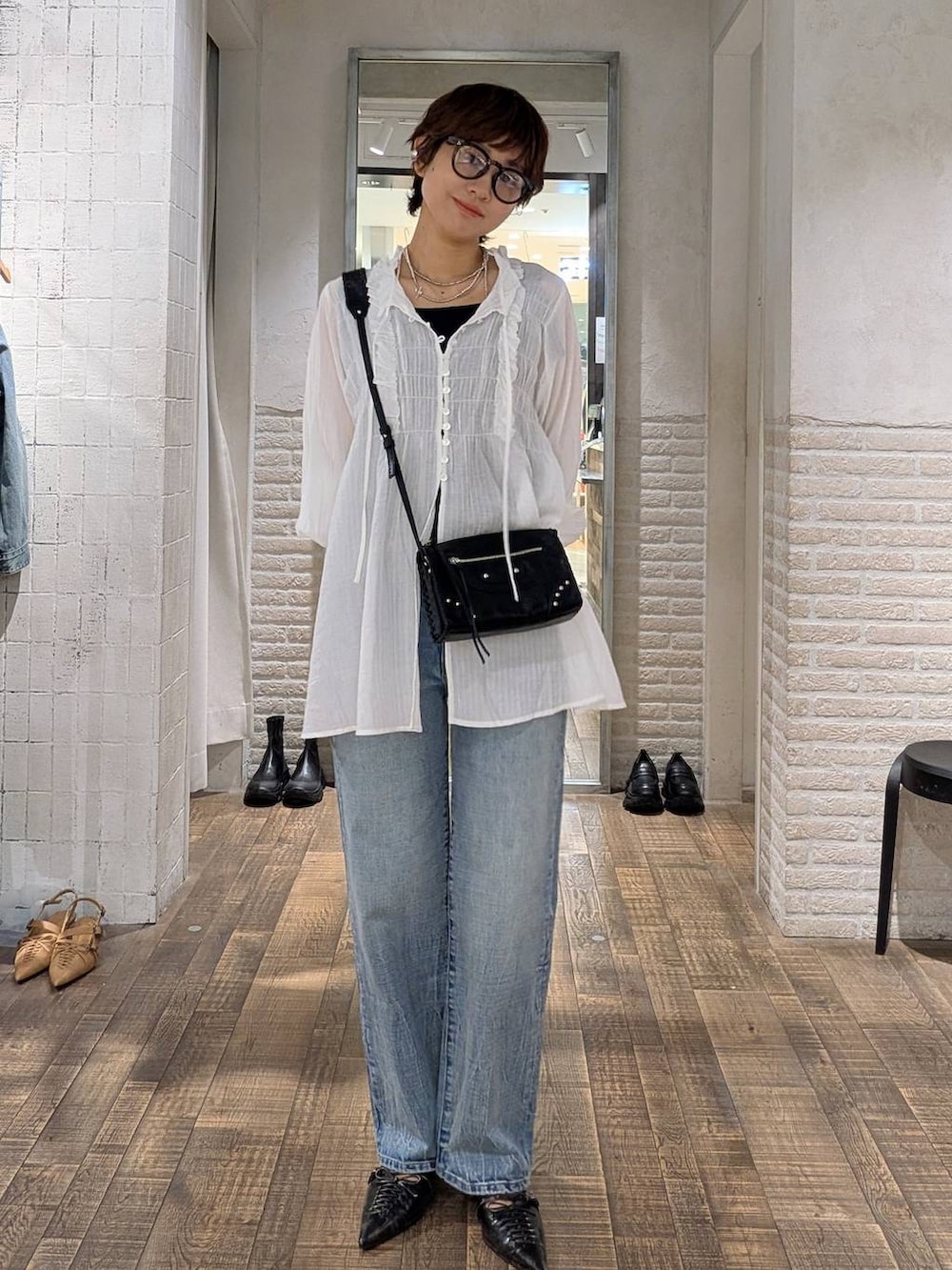 ブラック系のパンプス、ブルー系のデニムパンツ、ホワイト系のチュニックを着用したレディースの秋コーディネートの4枚目の写真