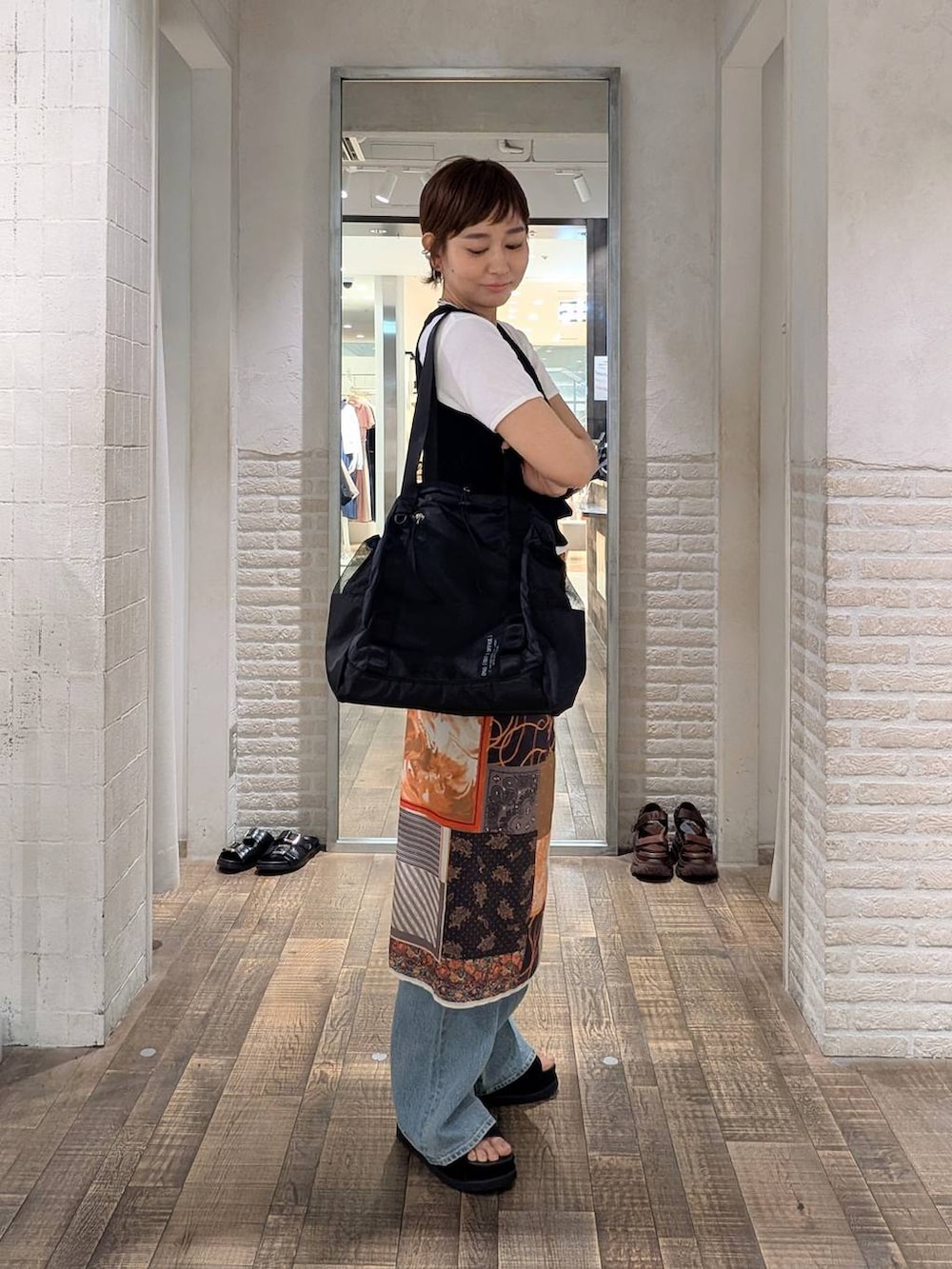 ブルー系のデニムパンツ、ホワイト系のTシャツ/カットソー、ブラック系のタンクトップを着用したレディースの春コーディネートの2枚目の写真
