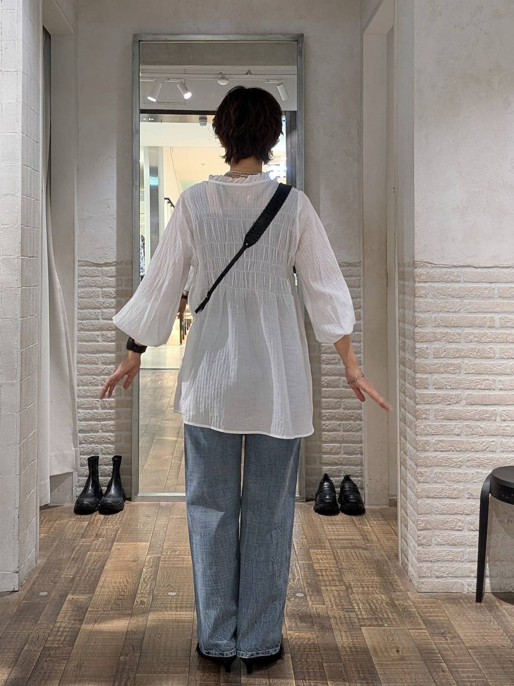 ブラック系のパンプス、ブルー系のデニムパンツ、ホワイト系のチュニックを着用したレディースの秋コーディネートの3枚目の写真