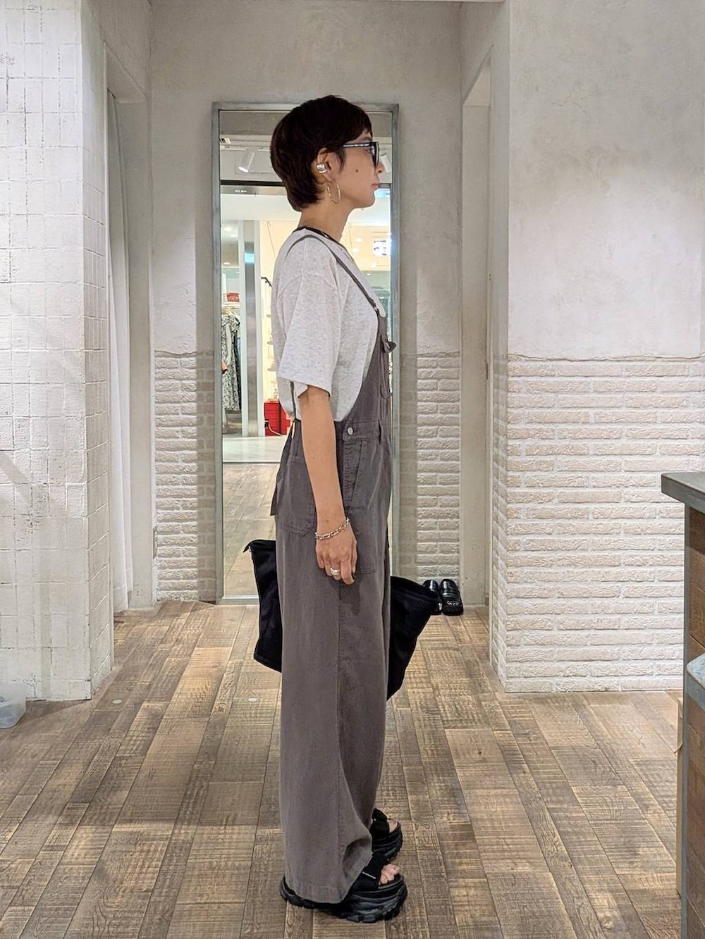 グレー系のTシャツ/カットソー、ブラック系のトートバッグ、ブラック系のサンダルを着用したレディースの夏コーディネートの2枚目の写真