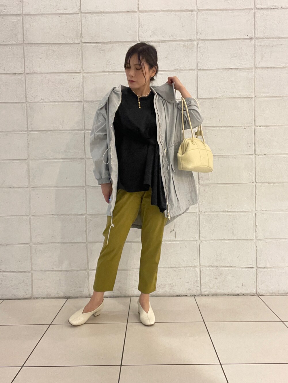 グレー系のモッズコート、ブラック系のTシャツ/カットソー、イエロー系のバッグを着用したレディースの春コーディネートの2枚目の写真