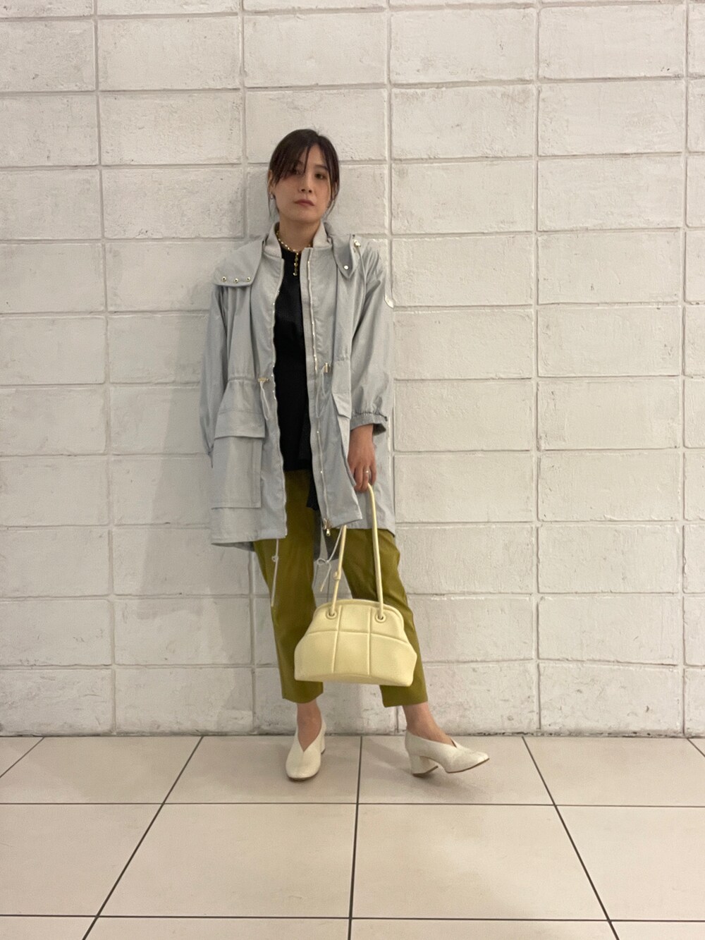 グレー系のモッズコート、ブラック系のTシャツ/カットソー、イエロー系のバッグを着用したレディースの春コーディネートの4枚目の写真