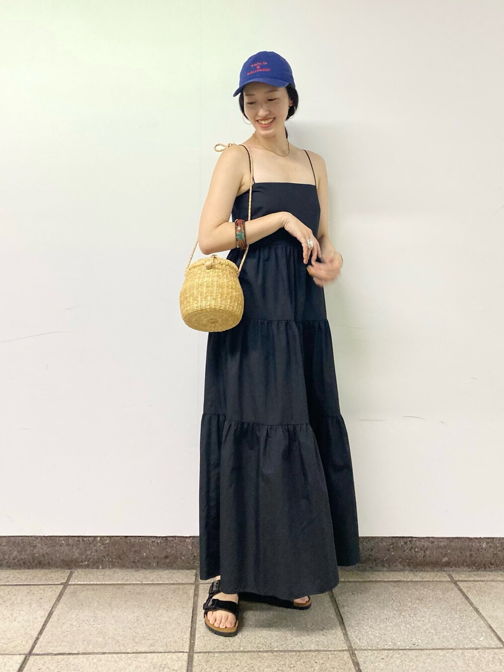 ブラック系のワンピース/ドレス、ブラック系のサンダル、ブルー系のキャップを着用したレディースの夏コーディネートの2枚目の写真