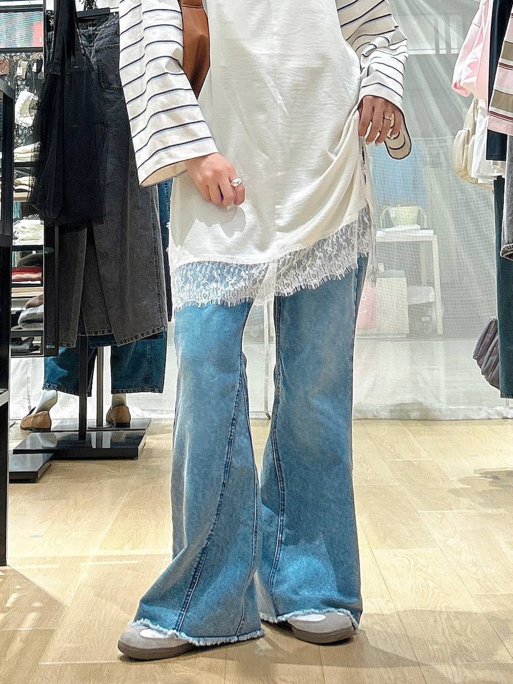 ブラウン系のショルダーバッグ、ブルー系のデニムパンツ、ベージュ系のワンピースを着用したレディースの冬コーディネートの3枚目の写真