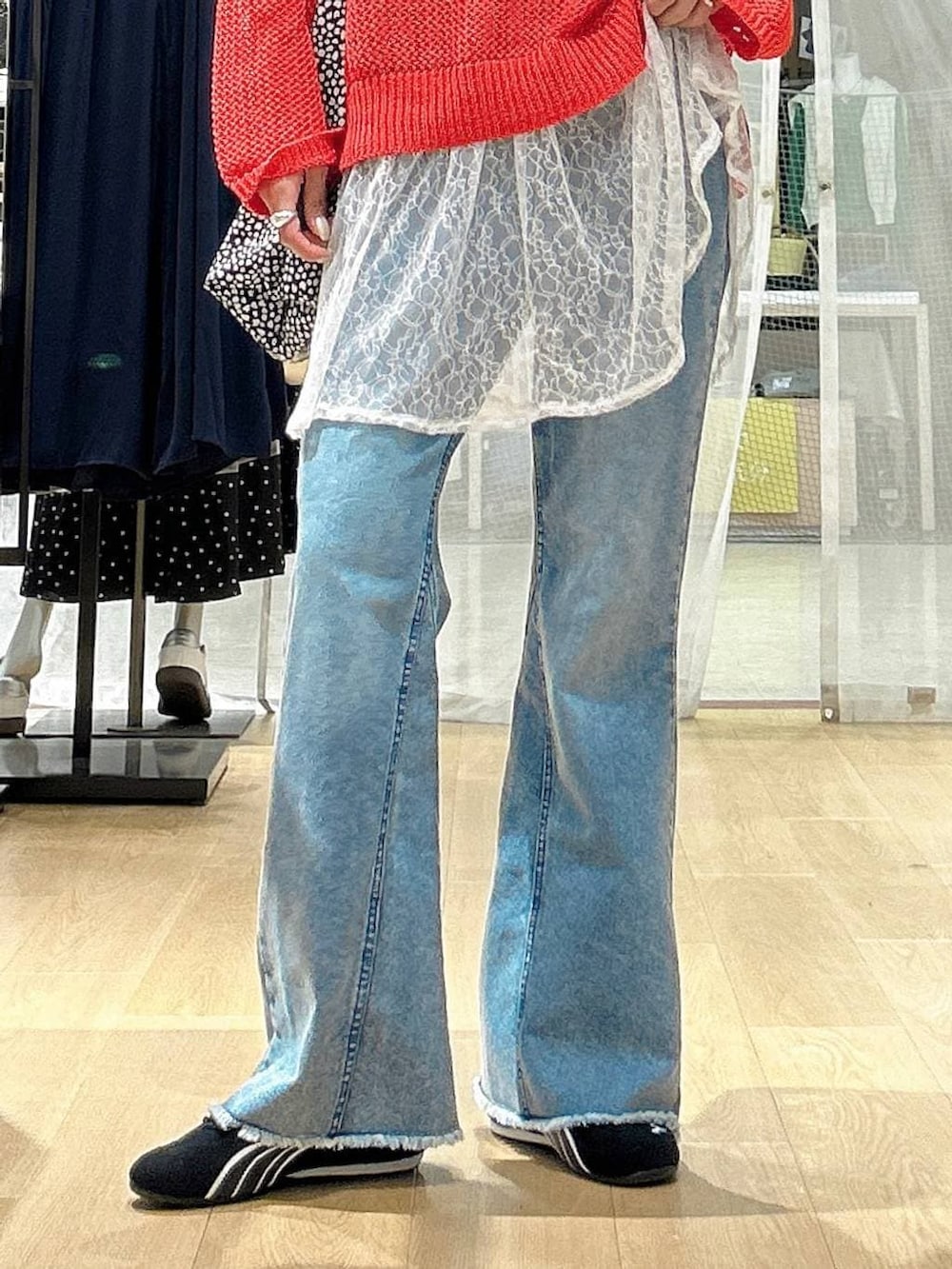 ブラック系のスニーカー、ブルー系のデニムパンツ、レッド系のニット/セーターを着用したレディースの春コーディネートの4枚目の写真