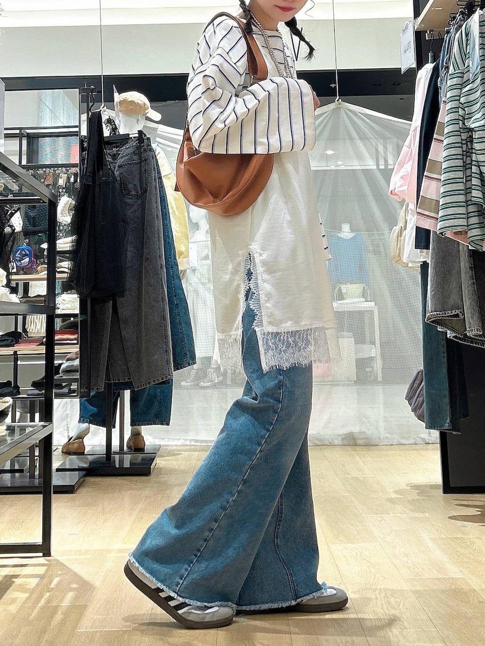 ブラウン系のショルダーバッグ、ブルー系のデニムパンツ、ベージュ系のワンピースを着用したレディースの冬コーディネートの4枚目の写真