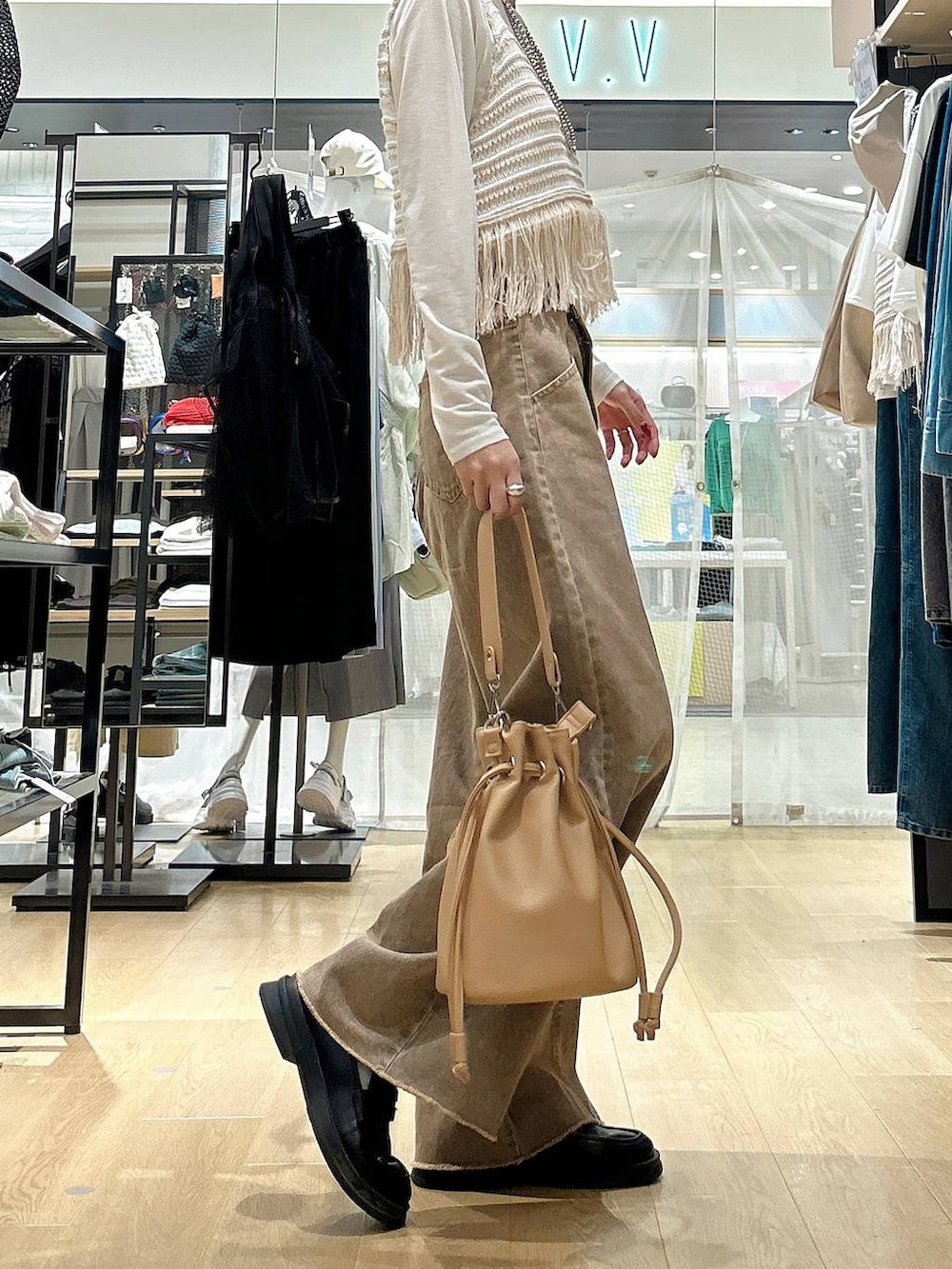 ホワイト系のTシャツ/カットソー、ブラウン系のショルダーバッグ、ベージュ系のベストを着用したレディースの春コーディネートの4枚目の写真