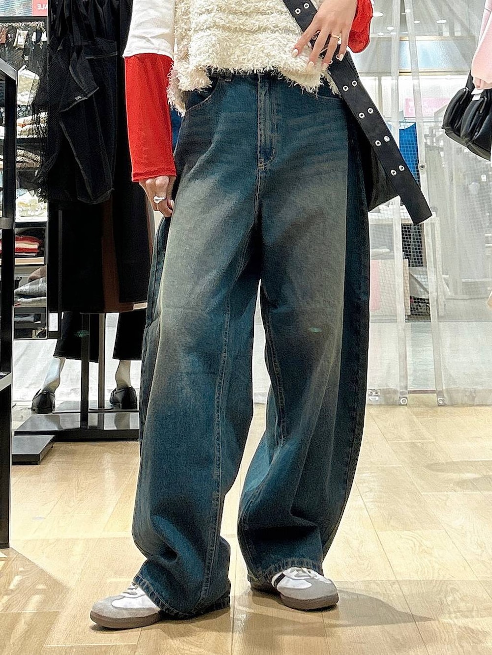 ブルー系のデニムパンツ、ブラック系のショルダーバッグ、ベージュ系のベストを着用したレディースの冬コーディネートの2枚目の写真