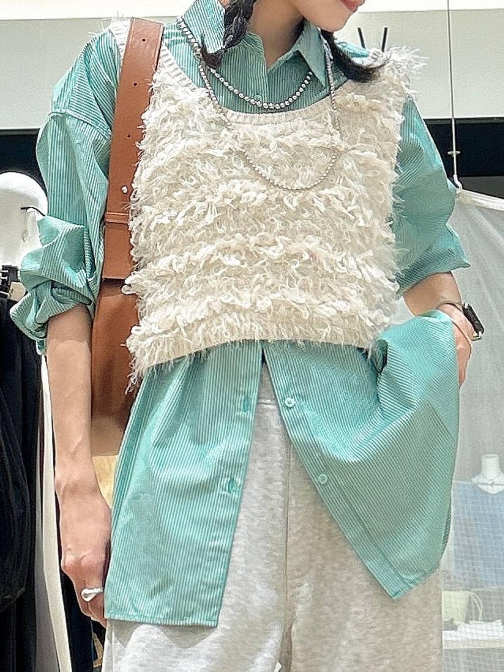 ブラウン系のショルダーバッグ、ホワイト系のベスト、グレー系のその他パンツを着用したレディースの冬コーディネートの2枚目の写真