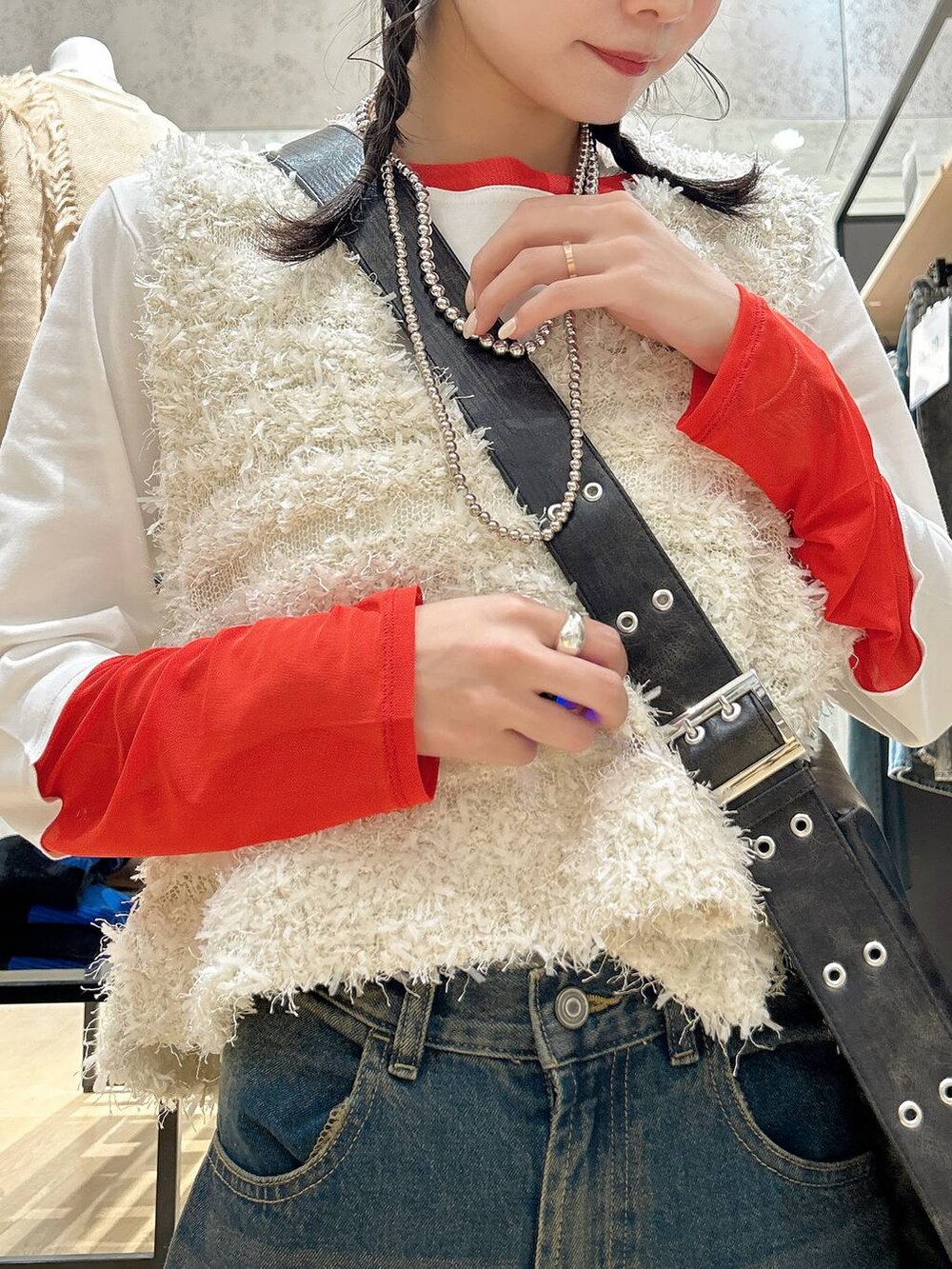 ブルー系のデニムパンツ、ブラック系のショルダーバッグ、ベージュ系のベストを着用したレディースの冬コーディネートの4枚目の写真