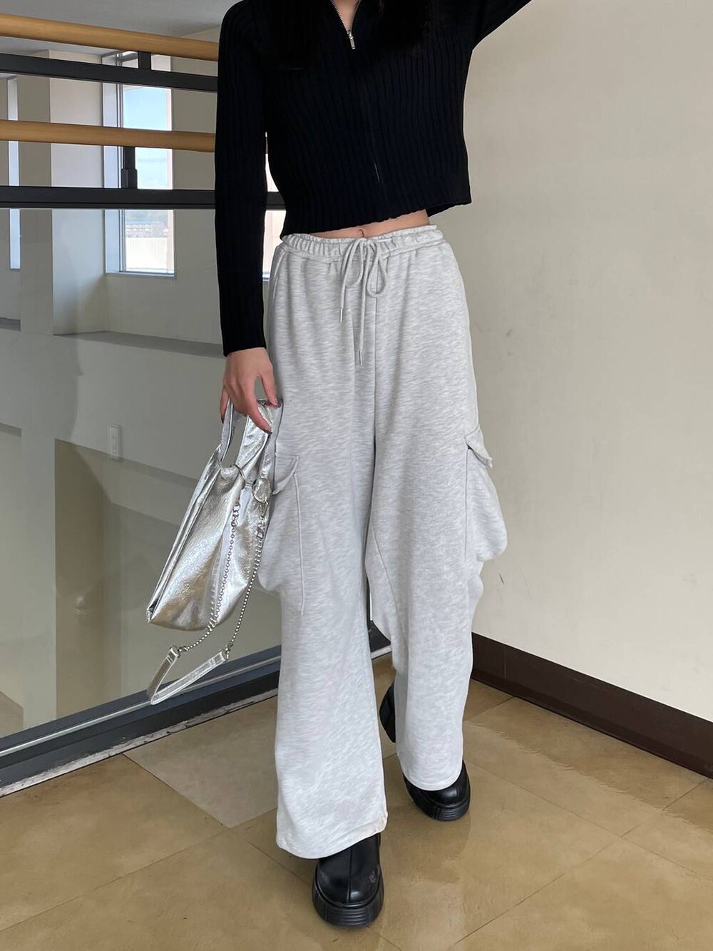 ブラック系のカーディガン/ボレロ、シルバー系のショルダーバッグ、グレー系のスウェットパンツを着用したレディースの春コーディネートの5枚目の写真