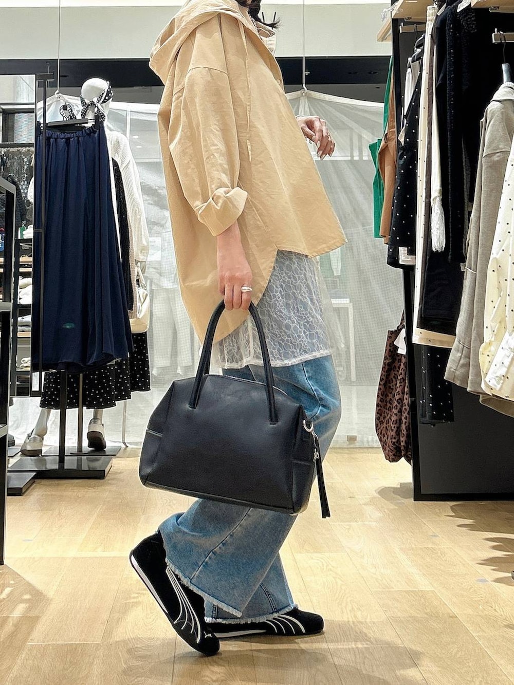 ブラック系のボストンバッグ、ブラック系のスニーカー、ブルー系のデニムパンツを着用したレディースの春コーディネートの4枚目の写真