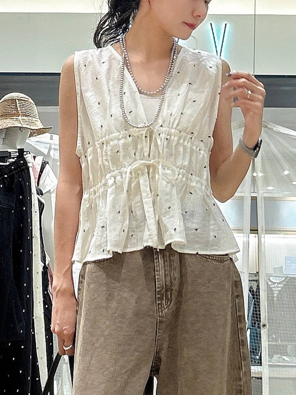 ブラウン系のデニムパンツ、ブラック系のショルダーバッグ、ホワイト系のその他トップスを着用したレディースの夏コーディネートの2枚目の写真